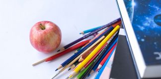 Colorful school supplies arranged with an apple on a white surface, ideal for education themes.