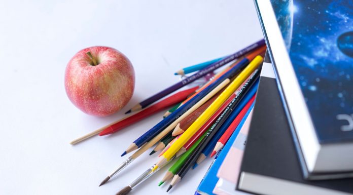 Colorful school supplies arranged with an apple on a white surface, ideal for education themes.