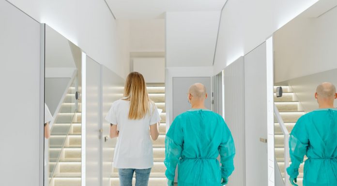 Baker Health Wellness Practice Opening in Hoboken Two medical practitioners walking down a bright clinic hallway with reflections in mirrors.