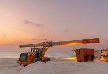 Bayonne’s Aging Water Pipe Under the Hackensack Is Getting a $32M Fix Dramatic view of beach construction site with heavy machinery at sunset.