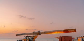 Dramatic view of beach construction site with heavy machinery at sunset.