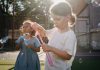 Two children joyfully creating bubbles, enjoying outdoor play under the sun.