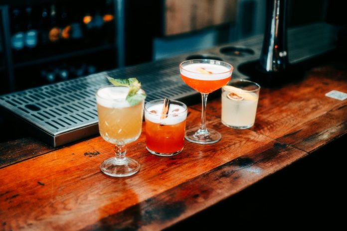best-bars-newark-night-out-2026 A vibrant selection of cocktails on a wooden bar, perfect for nightlife and parties.
