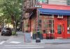 Cozy corner cafe and city street scene in New York with vibrant red facade and sidewalk seating.