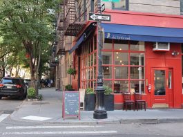 Cozy corner cafe and city street scene in New York with vibrant red facade and sidewalk seating.