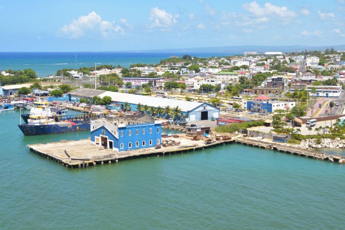 Aerial view of Puerto Plata harbor with blue buildings, ships, and a coastal town in the Dominican Republic.
