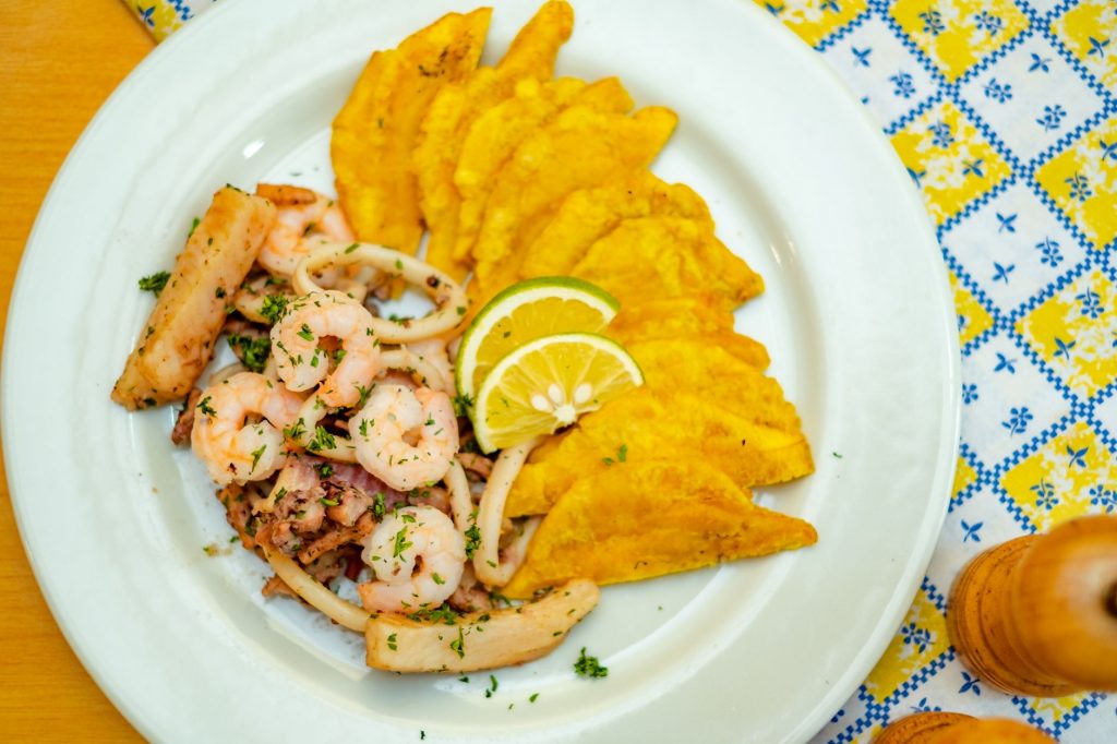 A vibrant plate of seafood and crispy plantains garnished with lemon slices, ready to savor.