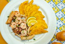 A vibrant plate of seafood and crispy plantains garnished with lemon slices, ready to savor.