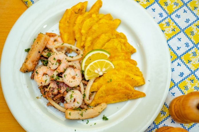 best-dominican-restaurants-west-new-york A vibrant plate of seafood and crispy plantains garnished with lemon slices, ready to savor.