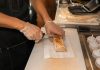 Best Halal Food in Union City, NJ: A Local’s Guide for 2026 A close-up of a person's hands slicing a shawarma on a kitchen counter, showcasing food preparation.