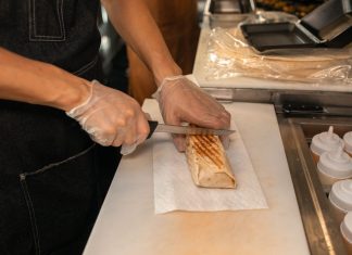 Best Halal Food in Union City, NJ: A Local’s Guide for 2026 A close-up of a person's hands slicing a shawarma on a kitchen counter, showcasing food preparation.
