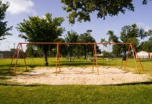 A vibrant playground with swings in a Houston park under a blue sky, perfect for family outings and leisure.