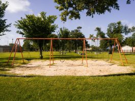 A vibrant playground with swings in a Houston park under a blue sky, perfect for family outings and leisure.