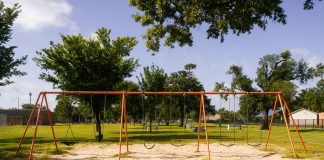 A vibrant playground with swings in a Houston park under a blue sky, perfect for family outings and leisure.