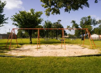 A vibrant playground with swings in a Houston park under a blue sky, perfect for family outings and leisure.
