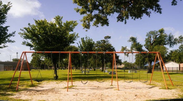 A vibrant playground with swings in a Houston park under a blue sky, perfect for family outings and leisure.