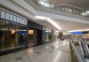 Spacious and contemporary mall interior with closed stores and escalator.