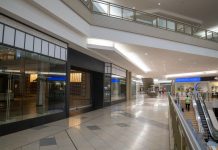 Spacious and contemporary mall interior with closed stores and escalator.