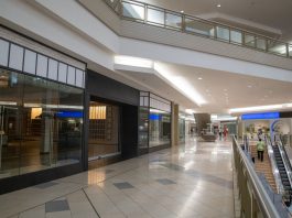 Spacious and contemporary mall interior with closed stores and escalator.