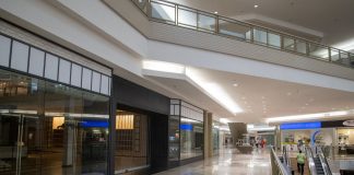 Spacious and contemporary mall interior with closed stores and escalator.