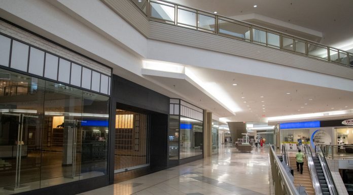 Spacious and contemporary mall interior with closed stores and escalator.