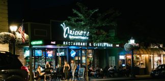 A bustling urban nightlife scene at a restaurant and oyster bar, with people dining outside.