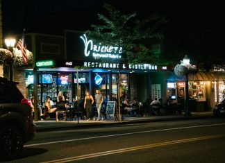 A bustling urban nightlife scene at a restaurant and oyster bar, with people dining outside.