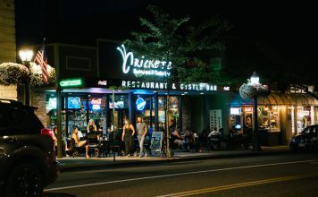 A bustling urban nightlife scene at a restaurant and oyster bar, with people dining outside.