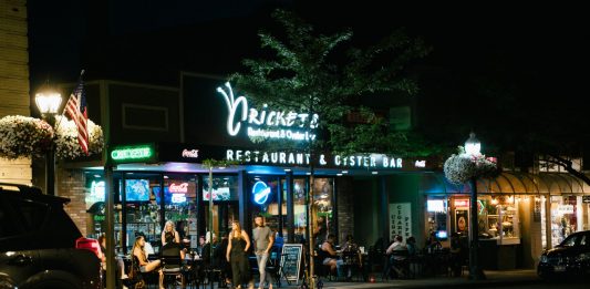 A bustling urban nightlife scene at a restaurant and oyster bar, with people dining outside.