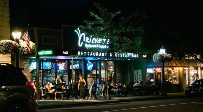 A bustling urban nightlife scene at a restaurant and oyster bar, with people dining outside.