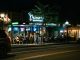 A bustling urban nightlife scene at a restaurant and oyster bar, with people dining outside.