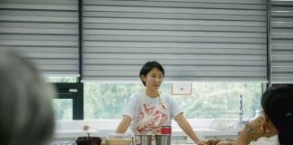 Chef leading a cooking class, explaining techniques to students in a bright, modern kitchen.