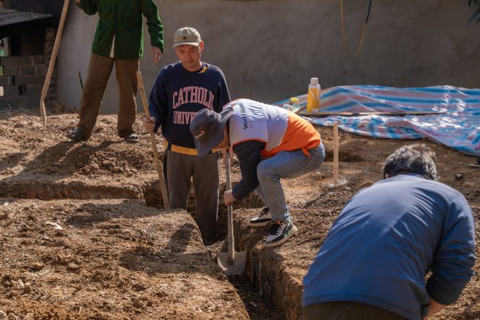 breaking-construction-begins-on-new-bayonne-food-p Volunteers working together to dig a trench at a construction site in daylight.