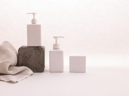 Stylish minimalist setup with cosmetic pump bottles and fabric on a white background, ideal for beauty product presentation.