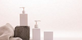 Stylish minimalist setup with cosmetic pump bottles and fabric on a white background, ideal for beauty product presentation.