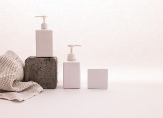 Stylish minimalist setup with cosmetic pump bottles and fabric on a white background, ideal for beauty product presentation.