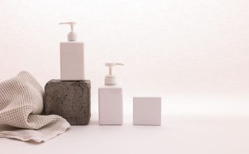 Stylish minimalist setup with cosmetic pump bottles and fabric on a white background, ideal for beauty product presentation.