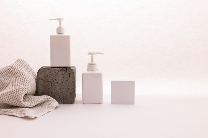 breaking-ethos-aesthetics-launches-new-september-b Stylish minimalist setup with cosmetic pump bottles and fabric on a white background, ideal for beauty product presentation.