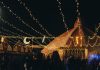 A vibrant evening market scene under string lights with people gathering in a lively atmosphere.