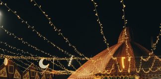 A vibrant evening market scene under string lights with people gathering in a lively atmosphere.