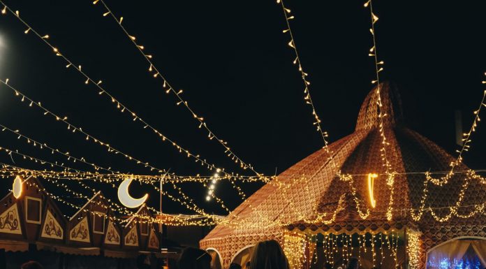 A vibrant evening market scene under string lights with people gathering in a lively atmosphere.