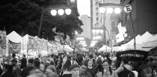Bustling street market with diverse crowd in black and white.