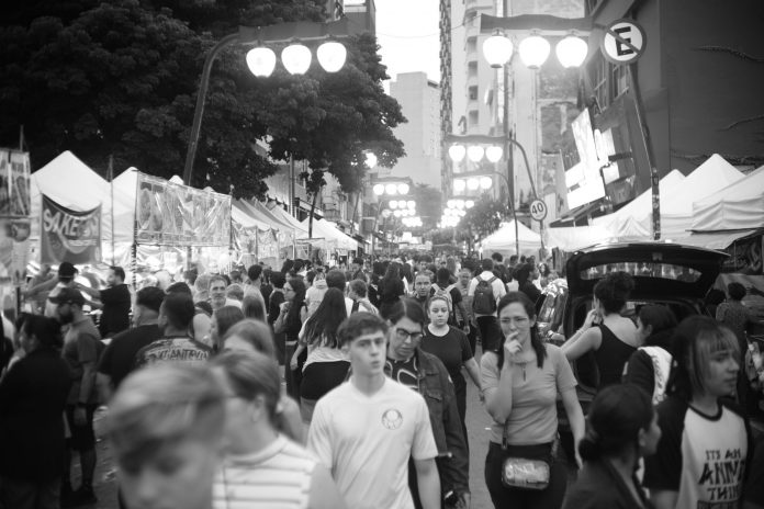 Bustling street market with diverse crowd in black and white.