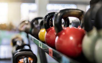 Close-up of colorful kettlebells on a rack in a modern gym indoors.