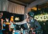 Bartender skillfully mixing a cocktail in a trendy neon-lit bar setting with lively ambiance.