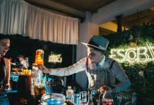 Bartender skillfully mixing a cocktail in a trendy neon-lit bar setting with lively ambiance.