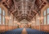 Elegant interior of a historic hall at the University of Manchester, showcasing intricate wooden beams and lighting.