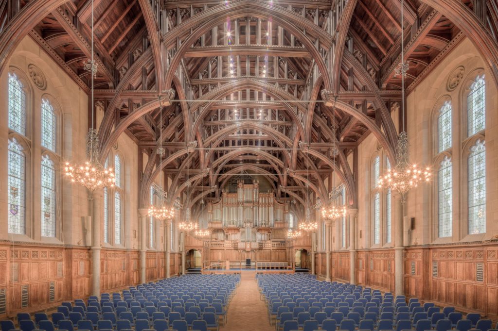 Elegant interior of a historic hall at the University of Manchester, showcasing intricate wooden beams and lighting.