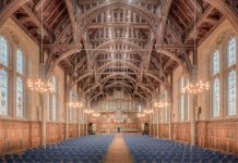 Elegant interior of a historic hall at the University of Manchester, showcasing intricate wooden beams and lighting.