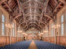 Elegant interior of a historic hall at the University of Manchester, showcasing intricate wooden beams and lighting.